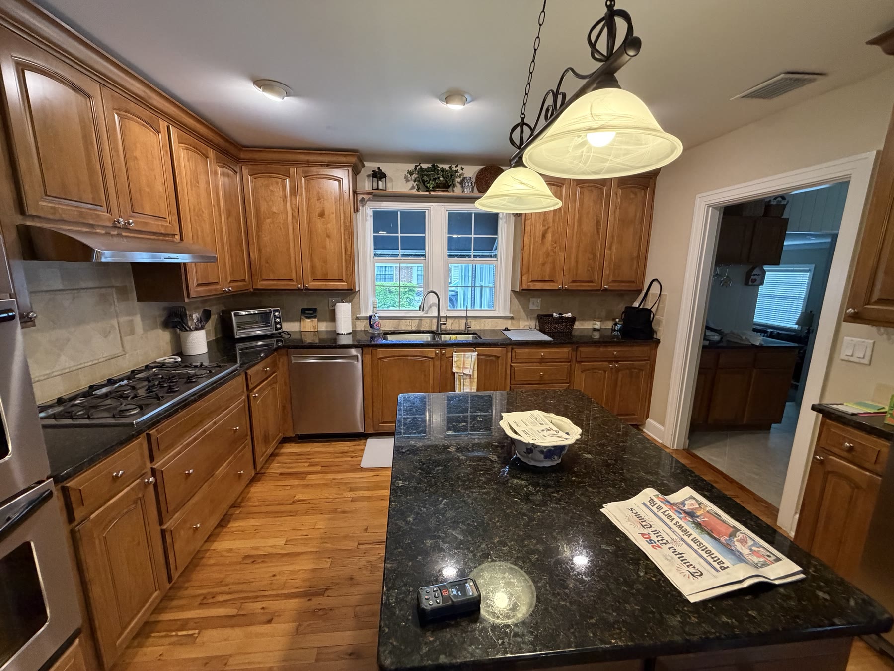 Dated South Tampa kitchen with honey oak raised-panel cabinets, dark granite and travertine backsplash before remodeling by 618 Construction