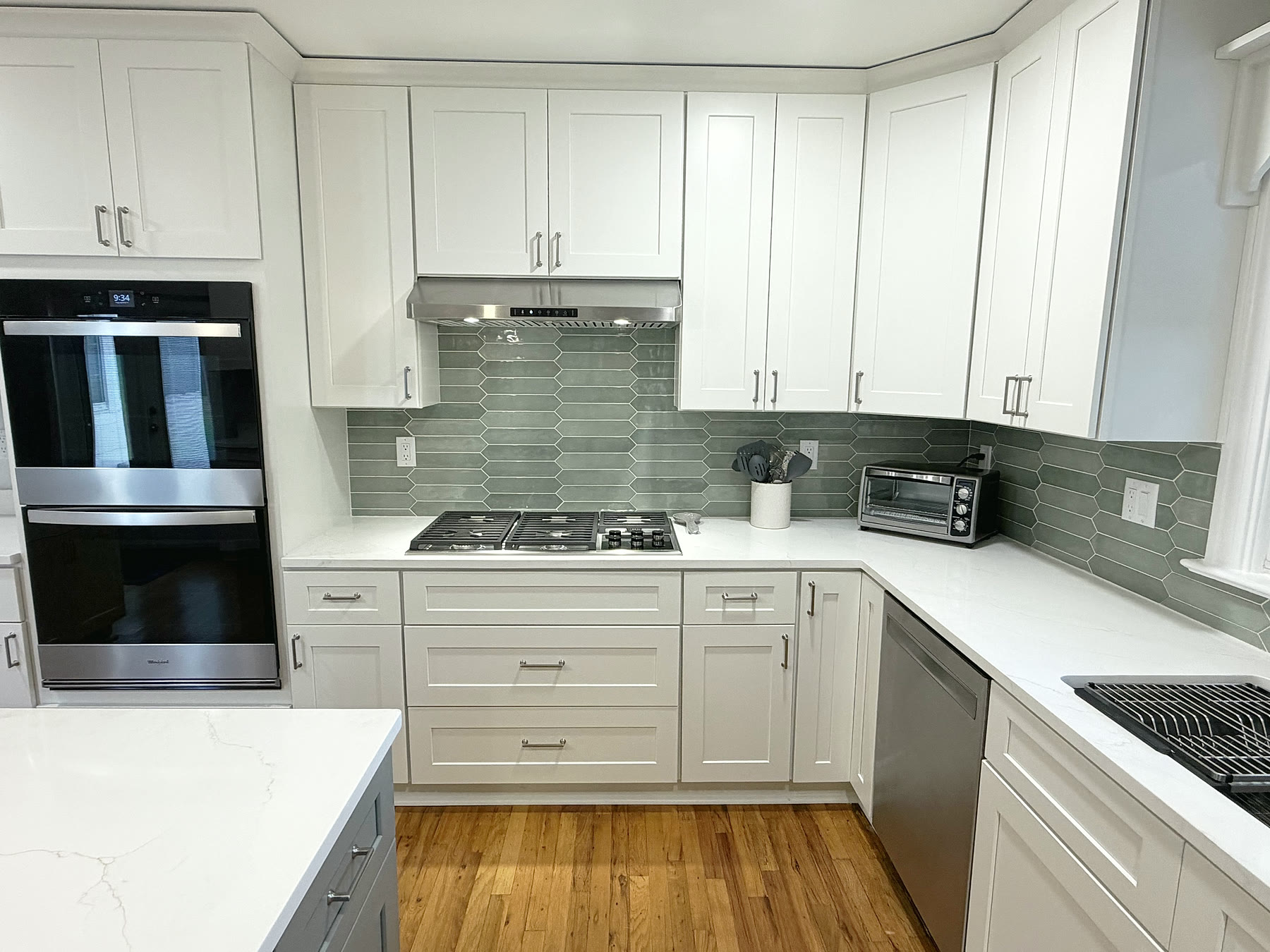 Gas cooktop with stainless hood and sage picket tile backsplash in a South Tampa kitchen remodel by 618 Construction