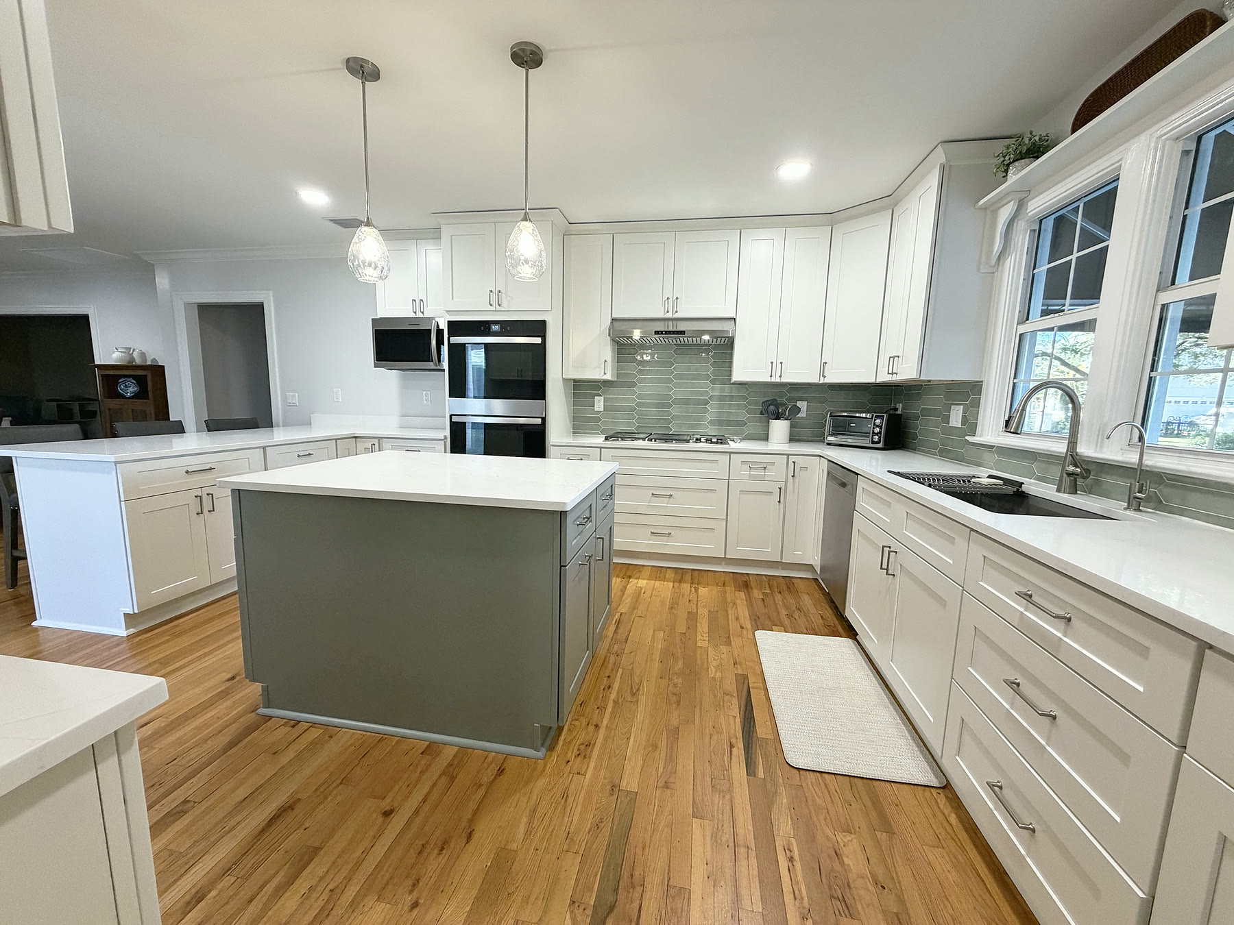 Finished South Tampa kitchen remodel with white shaker cabinets, sage picket backsplash and quartz island by 618 Construction