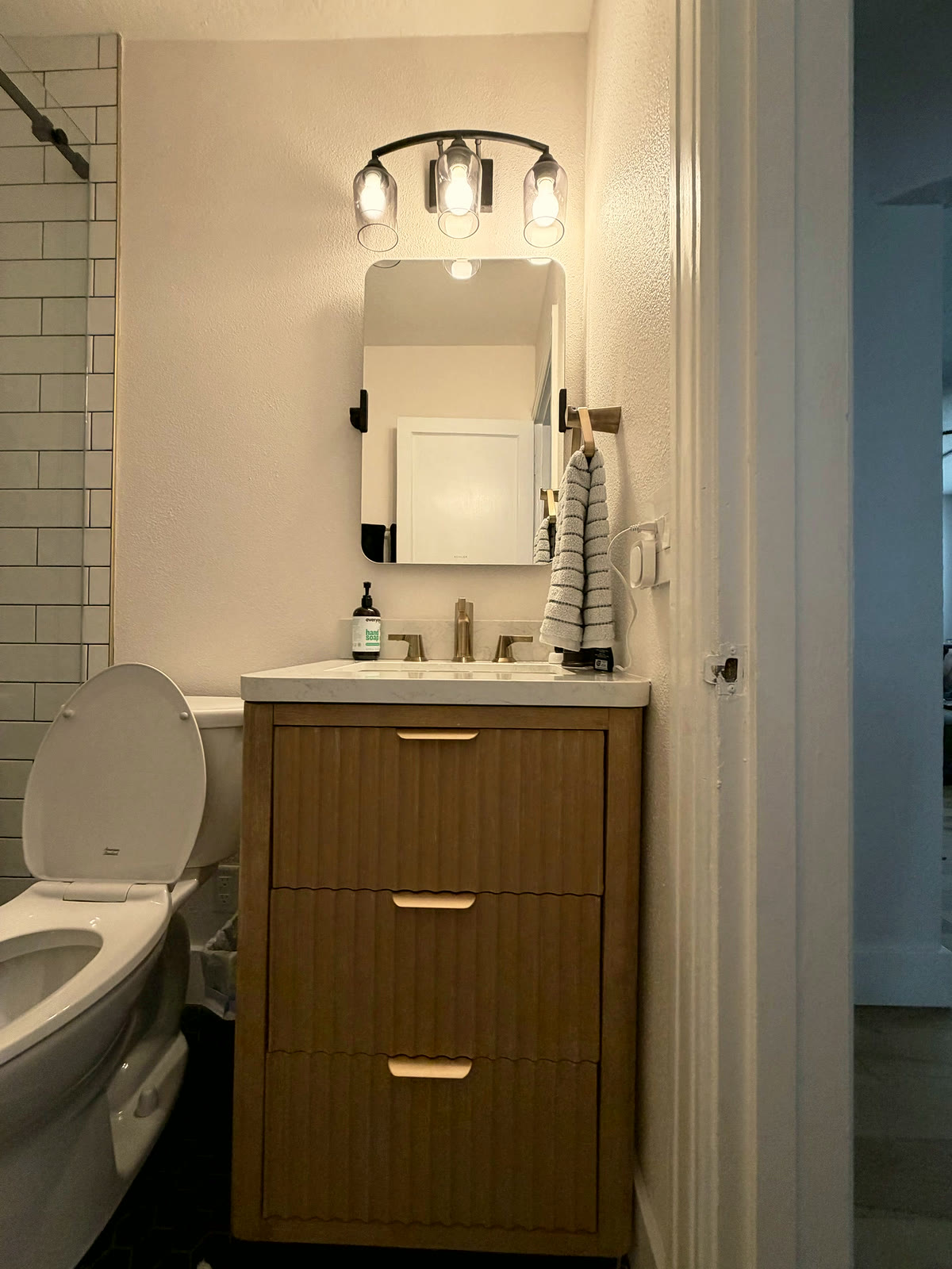 Wood vanity with quartz top and modern lighting in a St. Petersburg bathroom remodel by 618 Construction